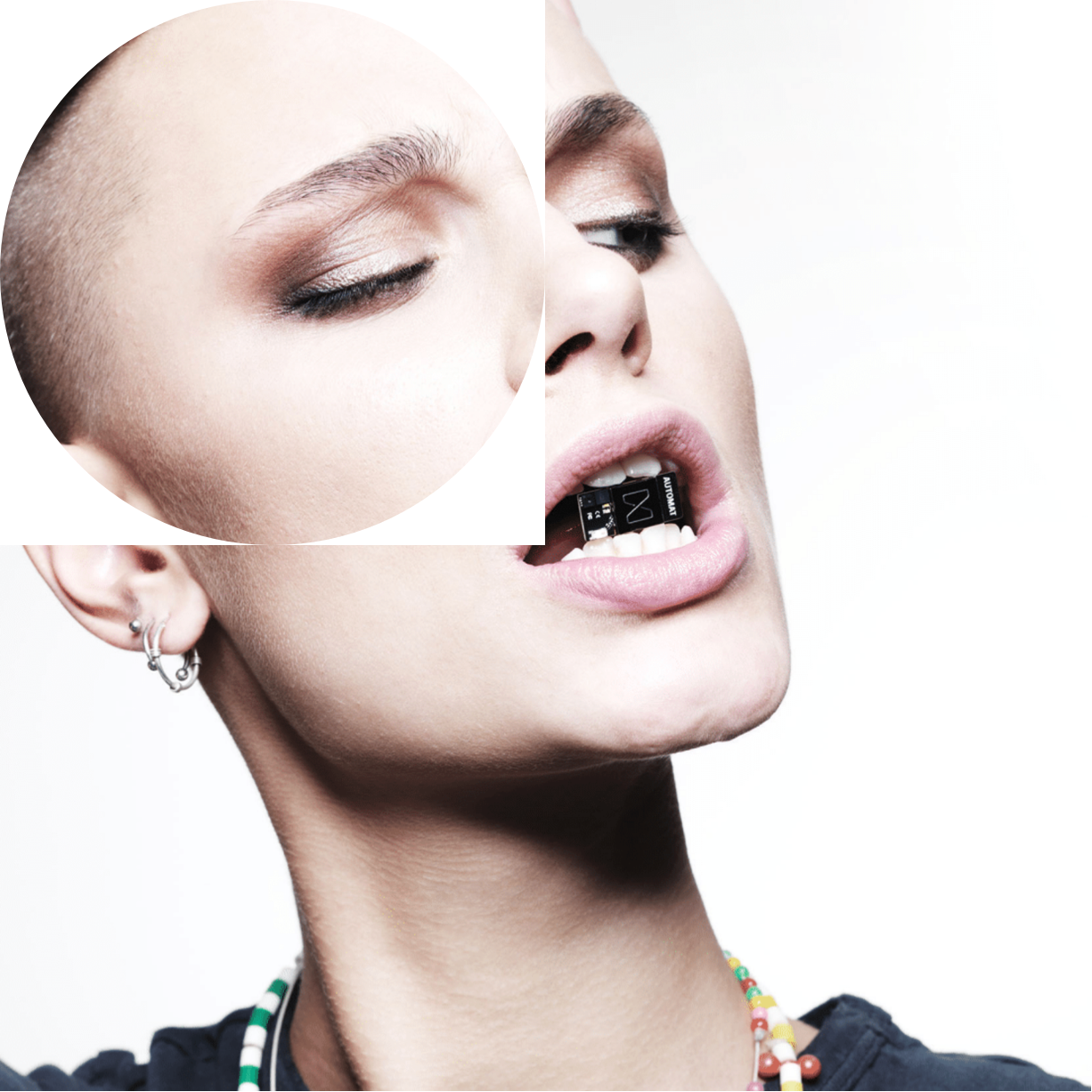 A woman with a shaved head holds the tiny Neue microchip between her teeth.